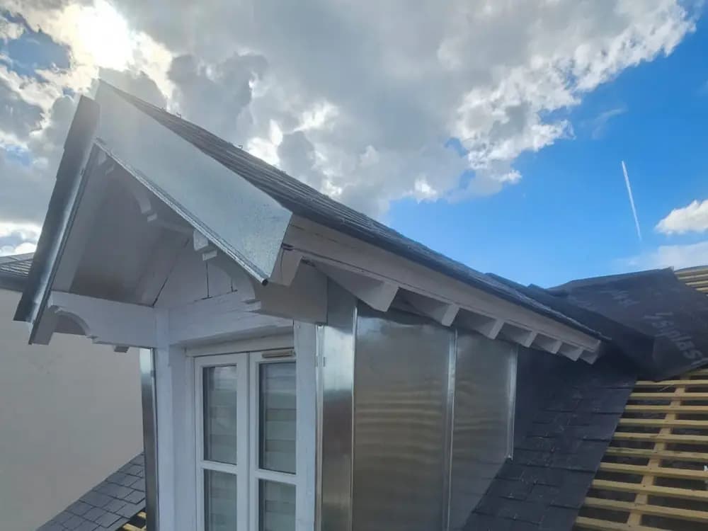 Lucarne rénovée avec habillage en zinc et couverture neuve en ardoise, sur une toiture en cours de réfection
